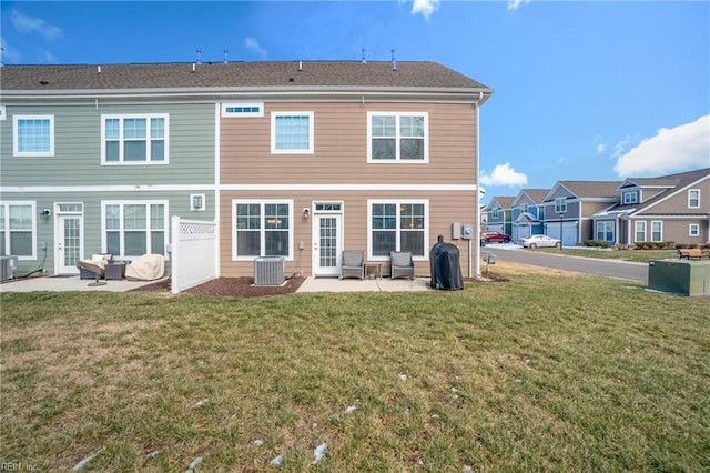 rear view of property with cooling unit, a yard, and a patio area