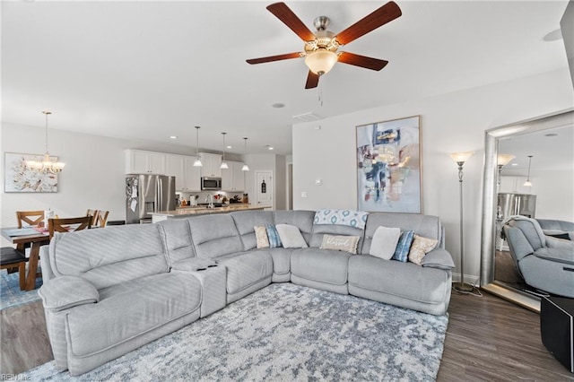 living room featuring dark wood-type flooring and ceiling fan with notable chandelier