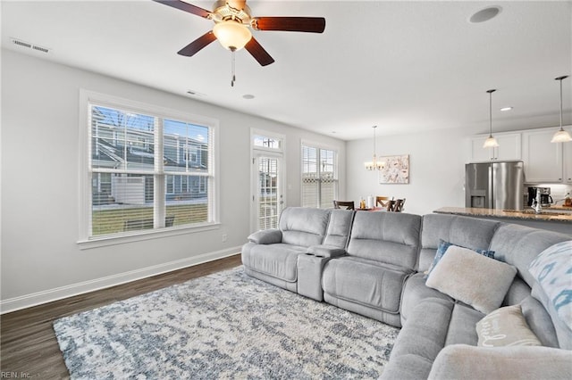 living room with dark hardwood / wood-style floors and ceiling fan with notable chandelier