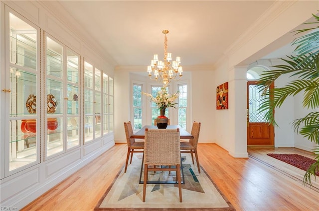 dining space with crown molding, a notable chandelier, and light wood-type flooring