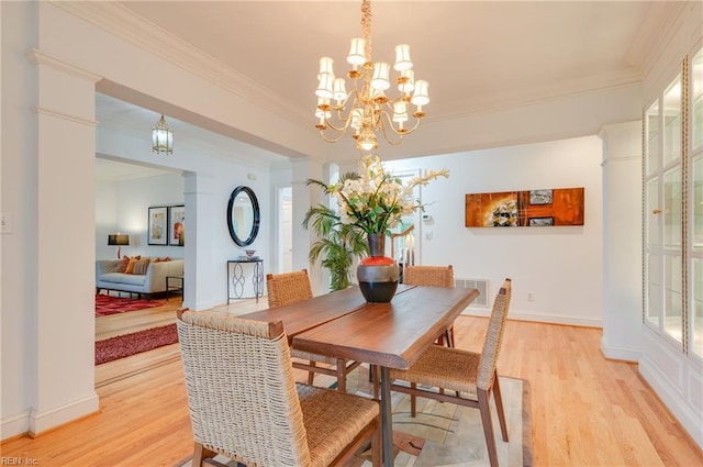 dining area featuring ornate columns, ornamental molding, a chandelier, and light wood-type flooring