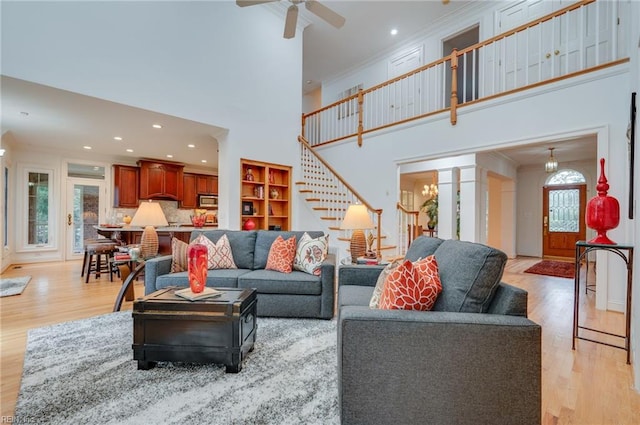 living room with crown molding, ceiling fan, a high ceiling, and light wood-type flooring