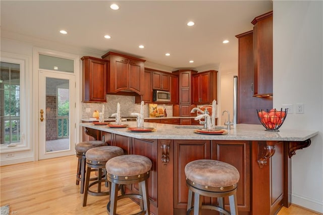 kitchen featuring sink, a breakfast bar, backsplash, kitchen peninsula, and light wood-type flooring