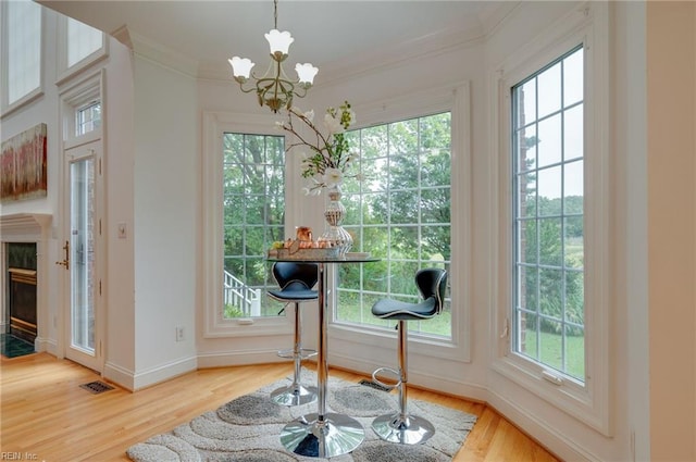 dining area featuring crown molding, a healthy amount of sunlight, a chandelier, and light hardwood / wood-style floors