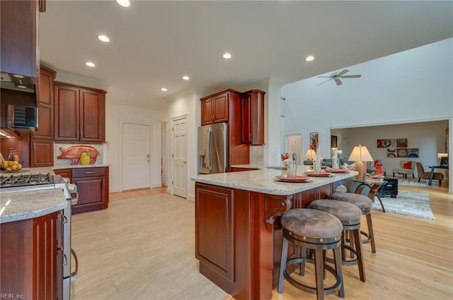 kitchen featuring stainless steel appliances, a breakfast bar area, ceiling fan, and decorative backsplash