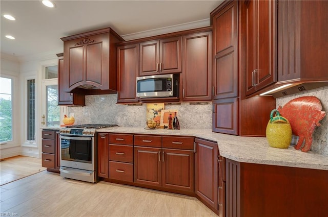 kitchen with light stone counters, tasteful backsplash, light wood-type flooring, ornamental molding, and stainless steel appliances