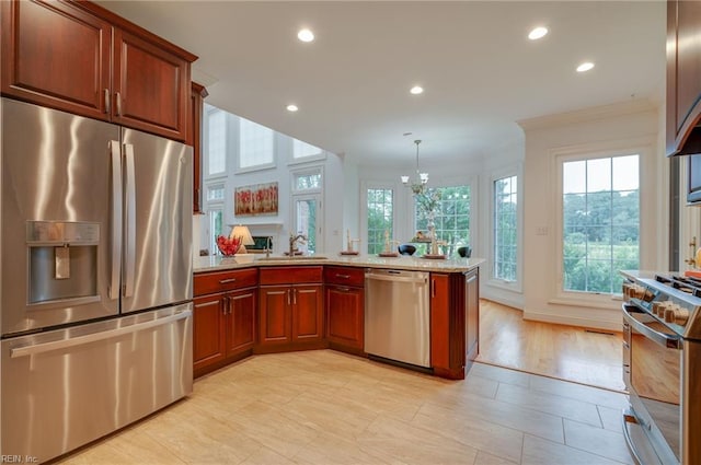 kitchen with sink, crown molding, stainless steel appliances, decorative light fixtures, and kitchen peninsula