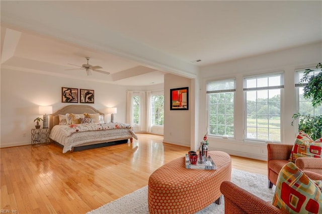 bedroom featuring ceiling fan, a tray ceiling, and light hardwood / wood-style floors