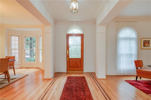 foyer featuring ornamental molding, plenty of natural light, hardwood / wood-style floors, and a notable chandelier