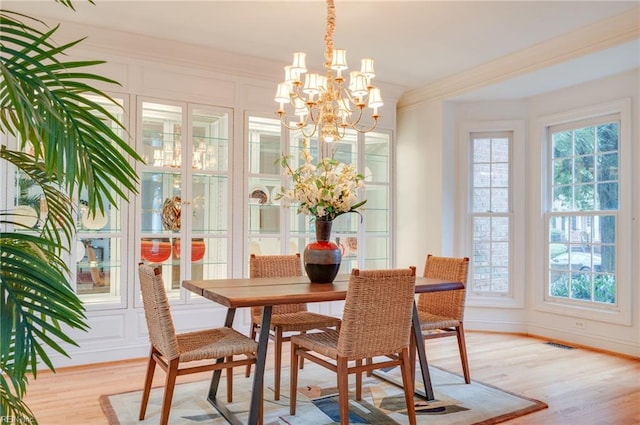 dining area featuring crown molding, light hardwood / wood-style floors, and a notable chandelier