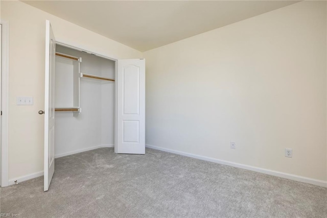 unfurnished bedroom featuring light colored carpet and a closet