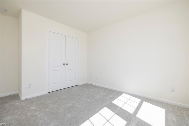 unfurnished bedroom with light colored carpet and a closet