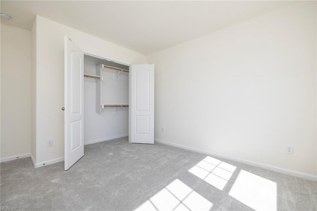 unfurnished bedroom featuring light carpet and a closet