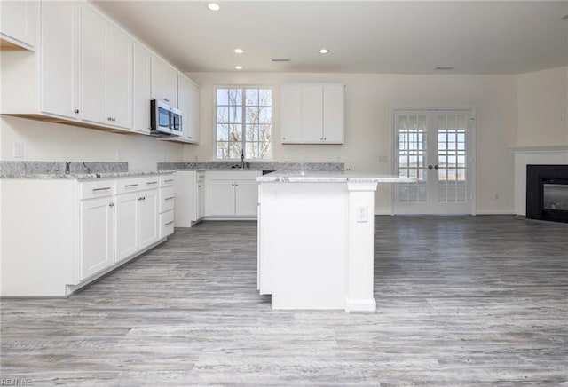 kitchen featuring white cabinetry, light stone countertops, a center island, and french doors