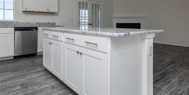 kitchen featuring light stone counters, stainless steel dishwasher, dark hardwood / wood-style floors, a kitchen island, and white cabinets