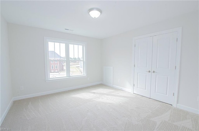 unfurnished bedroom with a closet and light carpet