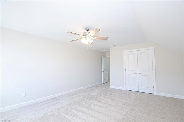 unfurnished bedroom featuring vaulted ceiling, light colored carpet, a closet, and ceiling fan