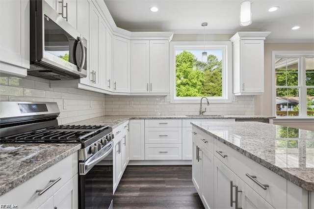 kitchen featuring sink, crown molding, hanging light fixtures, stainless steel appliances, and white cabinets