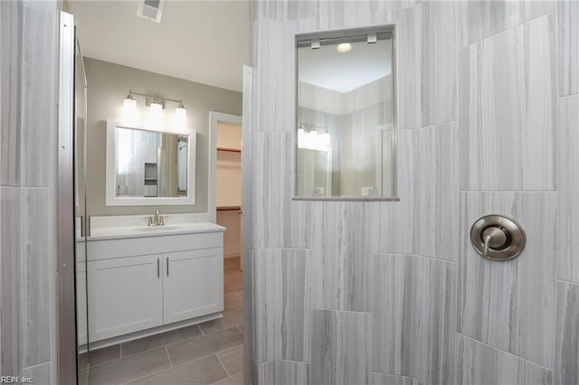 bathroom featuring vanity, a shower, and tile patterned floors