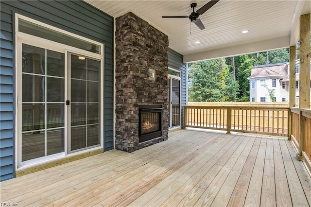 deck featuring ceiling fan and an outdoor stone fireplace