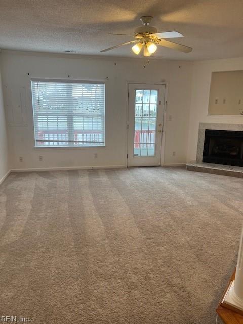 unfurnished living room with ceiling fan, carpet floors, and a textured ceiling