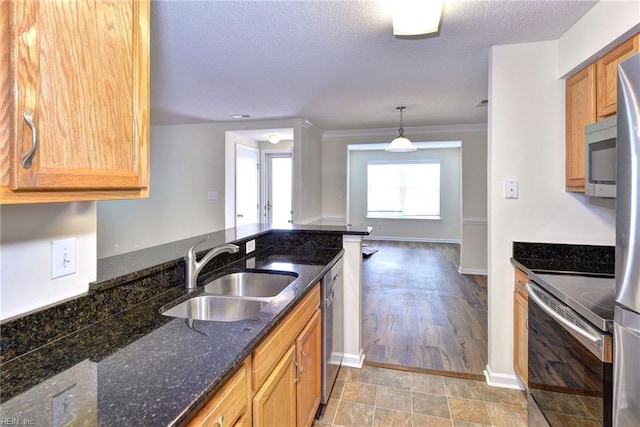 kitchen with sink, decorative light fixtures, a textured ceiling, appliances with stainless steel finishes, and dark stone counters