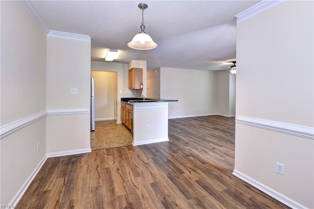 kitchen featuring dark wood-type flooring, a textured ceiling, fridge, pendant lighting, and ceiling fan