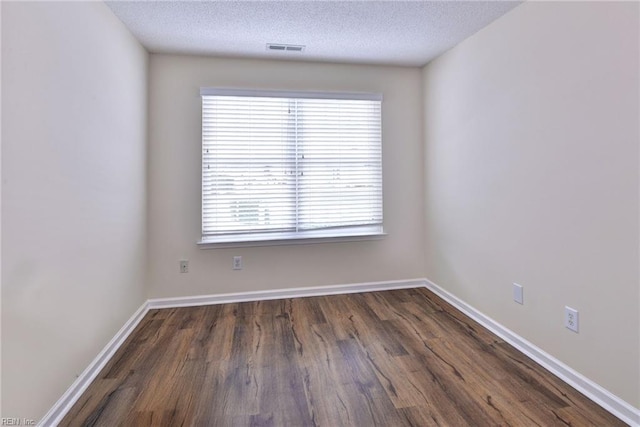 spare room featuring dark wood-type flooring and a textured ceiling