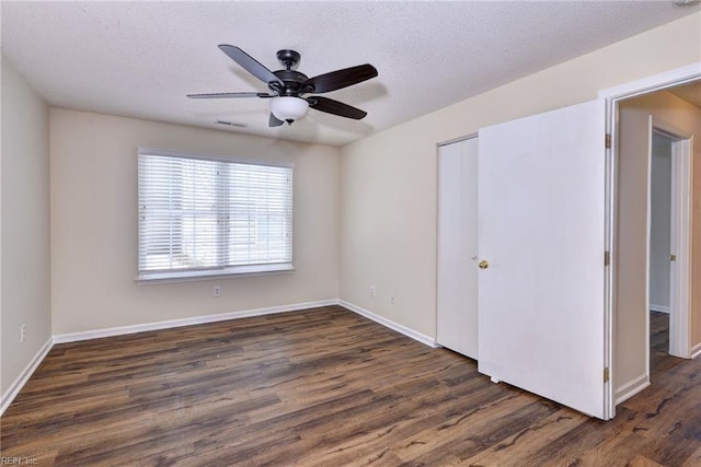 spare room with dark wood-type flooring, ceiling fan, and a textured ceiling