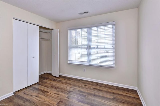 unfurnished bedroom featuring dark hardwood / wood-style flooring and a closet