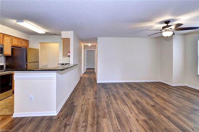 kitchen featuring dark wood-type flooring, stainless steel appliances, kitchen peninsula, and a textured ceiling