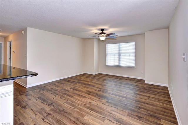 unfurnished living room with ceiling fan, dark hardwood / wood-style floors, and a textured ceiling