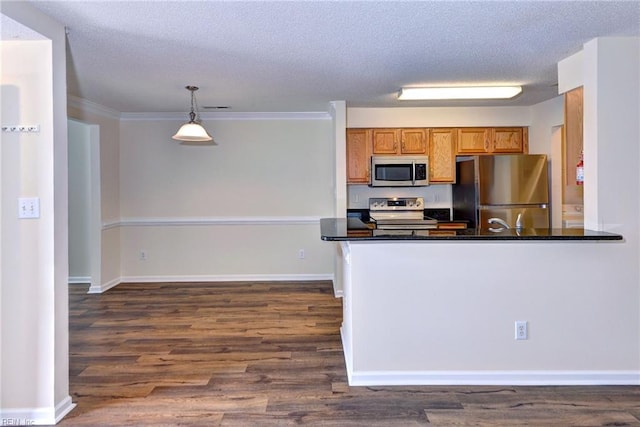 kitchen with appliances with stainless steel finishes, pendant lighting, kitchen peninsula, dark wood-type flooring, and a textured ceiling