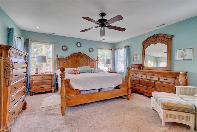 bedroom featuring light carpet, multiple windows, and ceiling fan