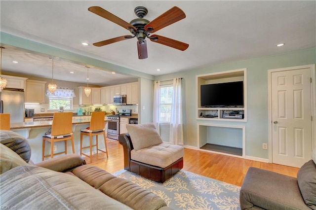 living room with ceiling fan and light wood-type flooring