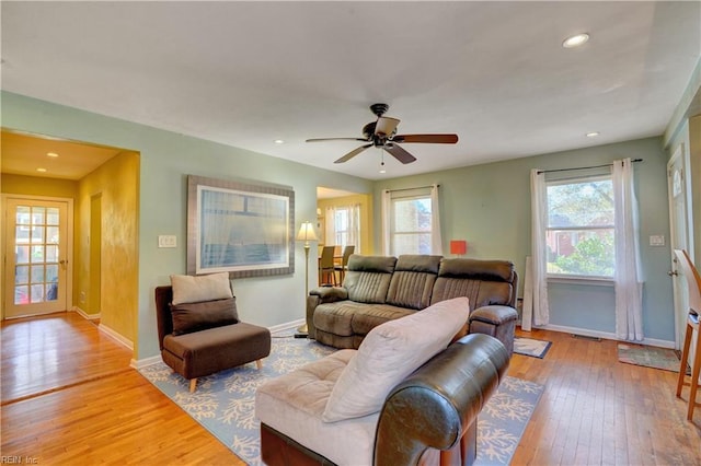 living room with ceiling fan, plenty of natural light, and light wood-type flooring