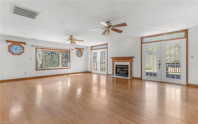 unfurnished living room featuring french doors, plenty of natural light, and light hardwood / wood-style flooring