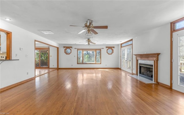 unfurnished living room with ceiling fan, a high end fireplace, and light wood-type flooring