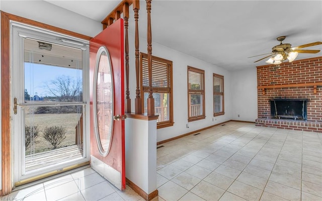 tiled entrance foyer featuring ceiling fan, a healthy amount of sunlight, and a fireplace