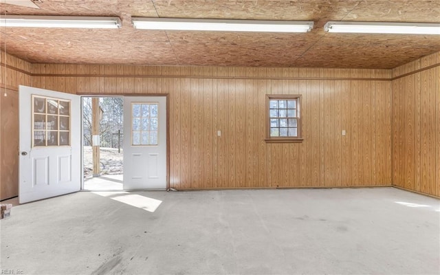 spare room with wooden walls and concrete flooring