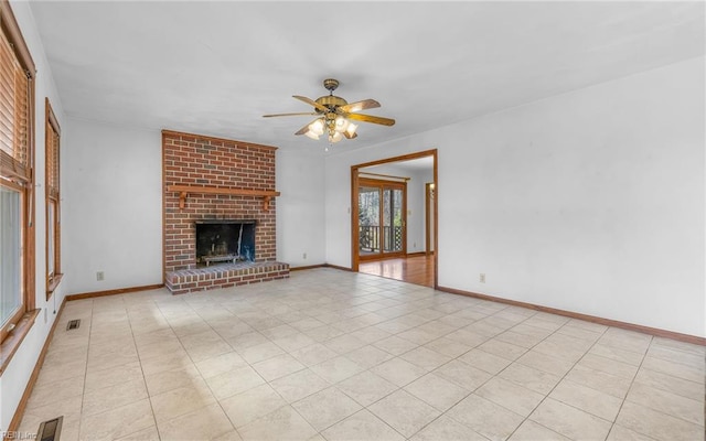 unfurnished living room with ceiling fan, a fireplace, and light tile patterned floors