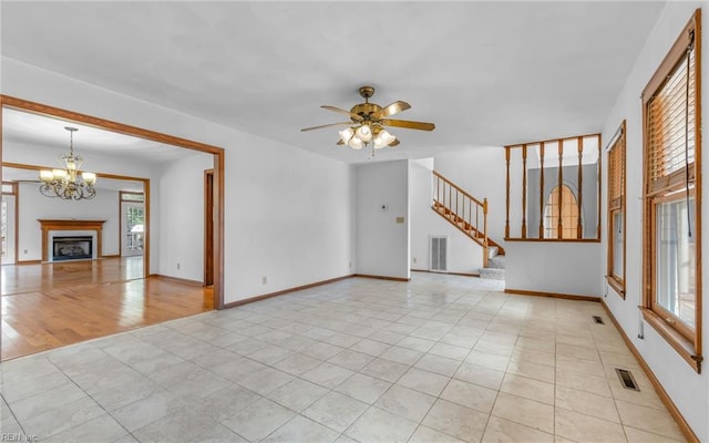 unfurnished living room with light tile patterned floors and ceiling fan with notable chandelier