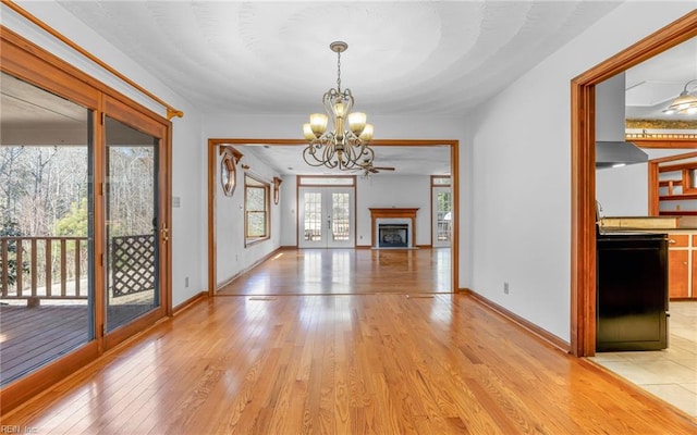 unfurnished living room with french doors, light hardwood / wood-style floors, and a notable chandelier