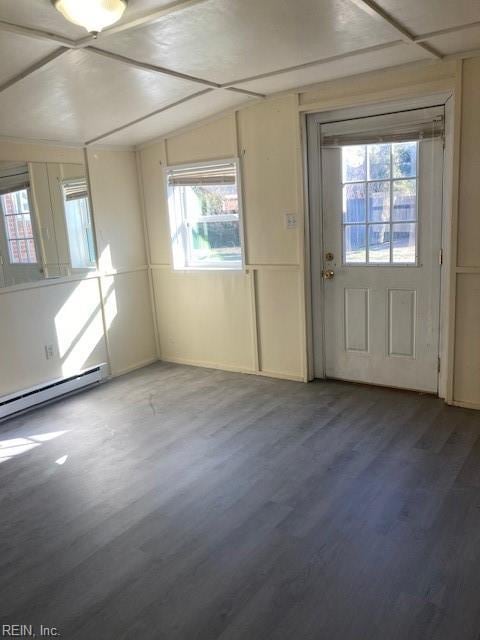 doorway featuring wood-type flooring, a baseboard radiator, a healthy amount of sunlight, and vaulted ceiling