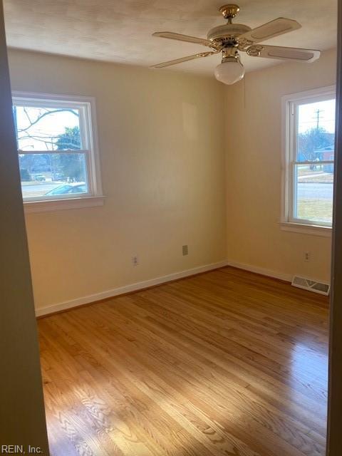 empty room with ceiling fan and light hardwood / wood-style flooring