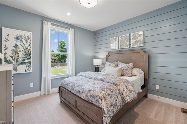 carpeted bedroom featuring multiple windows and wooden walls