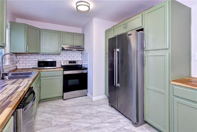 kitchen with tasteful backsplash, butcher block counters, sink, green cabinets, and stainless steel appliances