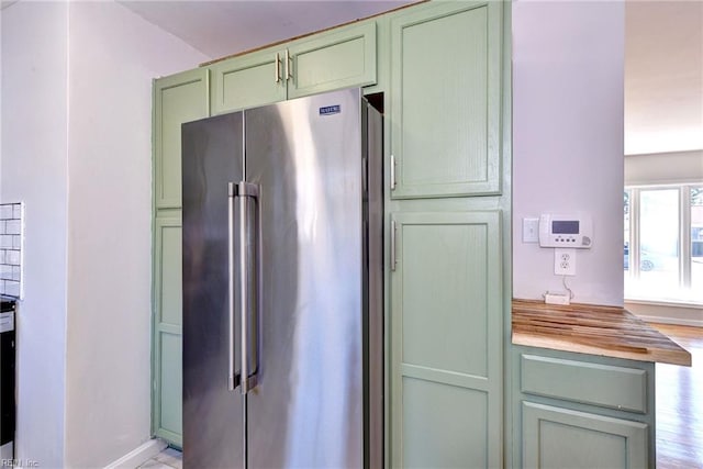 kitchen with wood counters, light hardwood / wood-style flooring, high quality fridge, and green cabinets