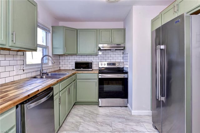 kitchen featuring appliances with stainless steel finishes, tasteful backsplash, sink, wooden counters, and green cabinets