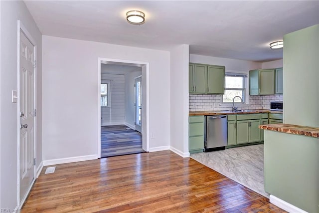 kitchen featuring butcher block countertops, tasteful backsplash, dishwasher, sink, and green cabinets